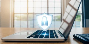 A laptop with a security shield icon, highlighting the 6 most common cybersecurity gaps in MSP assessments.
